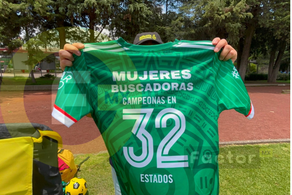 Activista muestra una camiseta verde con la leyenda “Mujeres buscadoras, campeonas en 32 estados”.